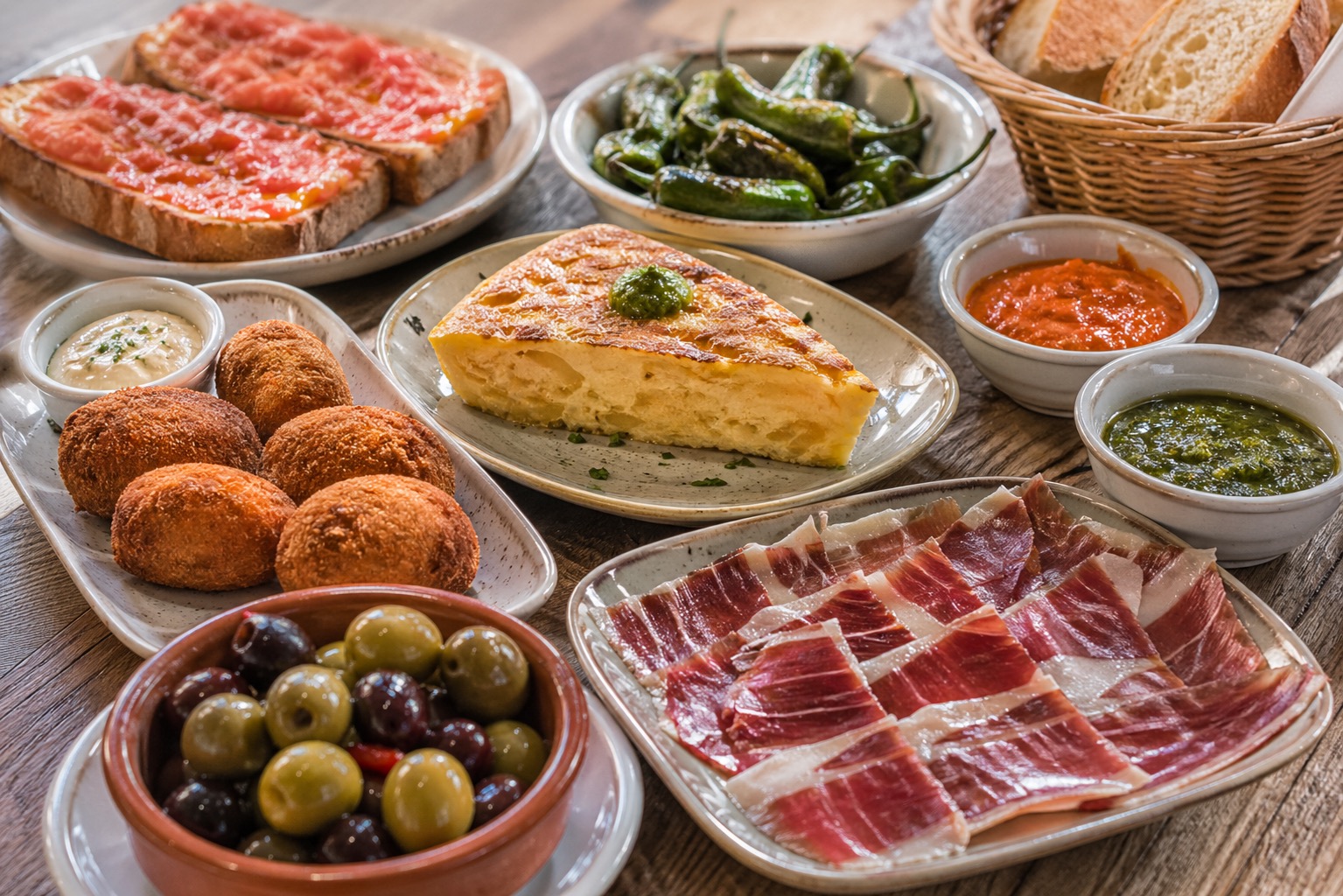 Spanish tapas with croquetas, tortilla, cured ham, olives, pan con tomate, peppers, and mojo.